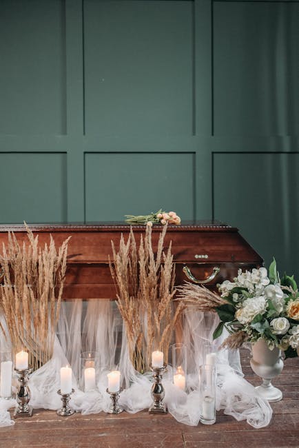 A floral arrangement featuring white, cream, and blush roses, along with white hydrangeas and greenery, placed in a white ceramic vase on a wooden floor. The flowers are part of a floral gift or decor